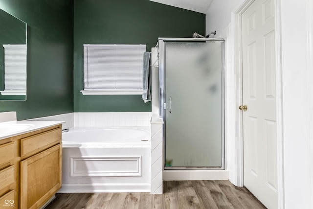 full bathroom featuring vanity, a shower stall, a bath, and wood finished floors