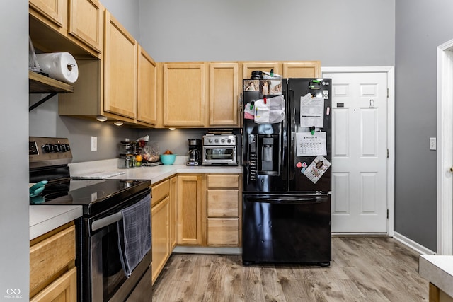 kitchen featuring black fridge with ice dispenser, light brown cabinets, light countertops, and electric stove