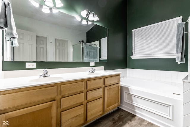 full bath featuring double vanity, a shower stall, a garden tub, and a sink