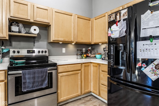 kitchen with light brown cabinets, light countertops, stainless steel range with electric stovetop, light wood-type flooring, and black fridge