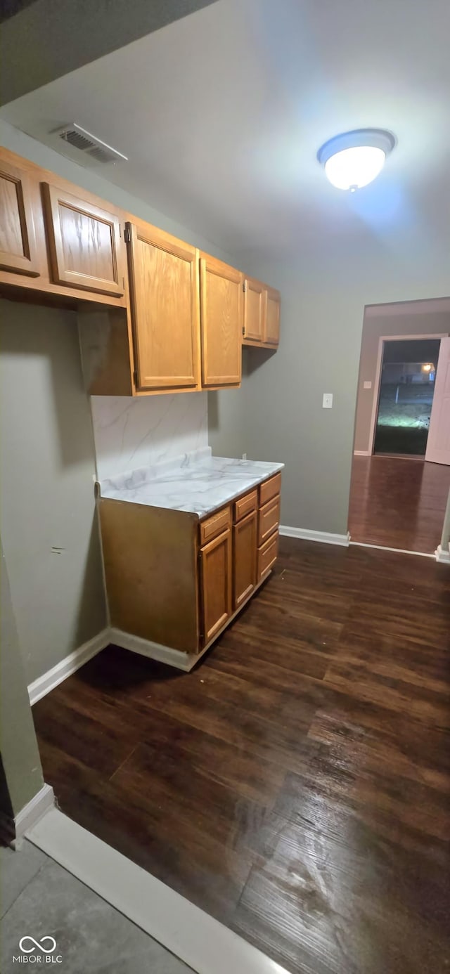 kitchen with light countertops, dark wood-style floors, visible vents, and baseboards