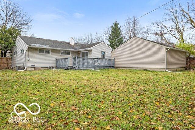 back of property featuring a lawn, a chimney, a deck, and fence