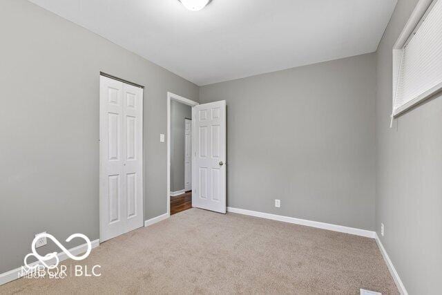 unfurnished bedroom with carpet, baseboards, and a closet