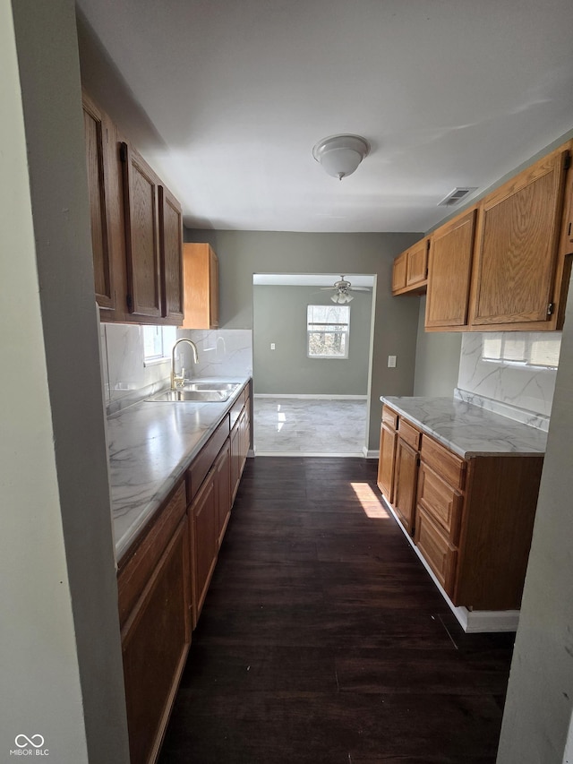 kitchen featuring visible vents, backsplash, a sink, light countertops, and dark wood-style flooring