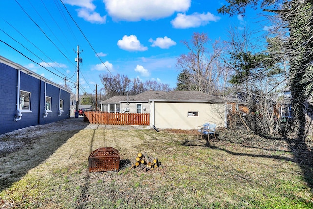 back of property with a yard, a fire pit, a wooden deck, and a shingled roof