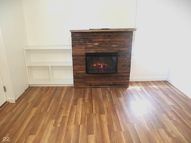 details featuring a glass covered fireplace, wood finished floors, and baseboards