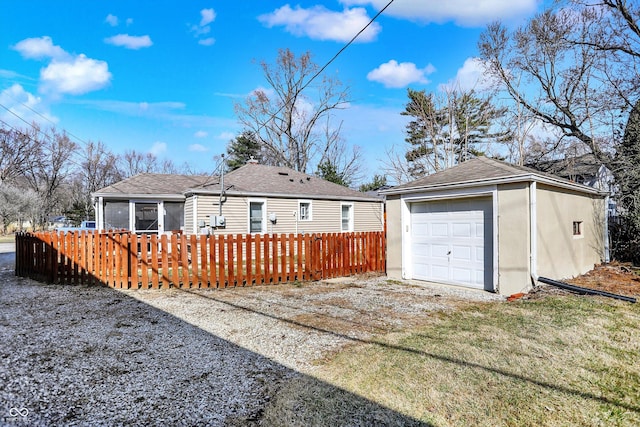 rear view of house featuring an outbuilding, fence, a garage, and driveway