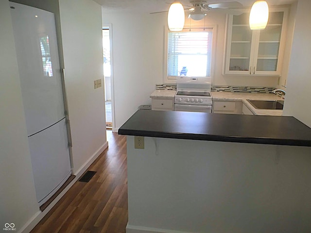 kitchen featuring a sink, a peninsula, electric range, white cabinetry, and dark wood-style flooring