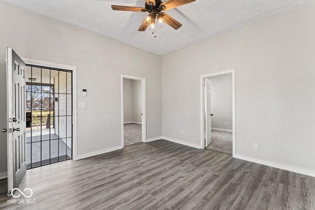 unfurnished room with a textured ceiling, baseboards, ceiling fan, and wood finished floors