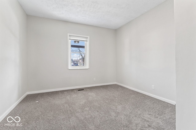 carpeted empty room featuring visible vents, baseboards, and a textured ceiling