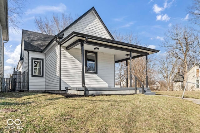 view of front of home with a porch, fence, a front lawn, and roof with shingles