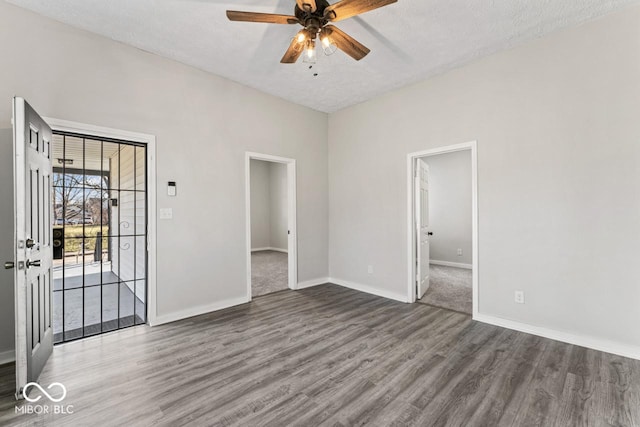 unfurnished room with a textured ceiling, baseboards, a ceiling fan, and wood finished floors