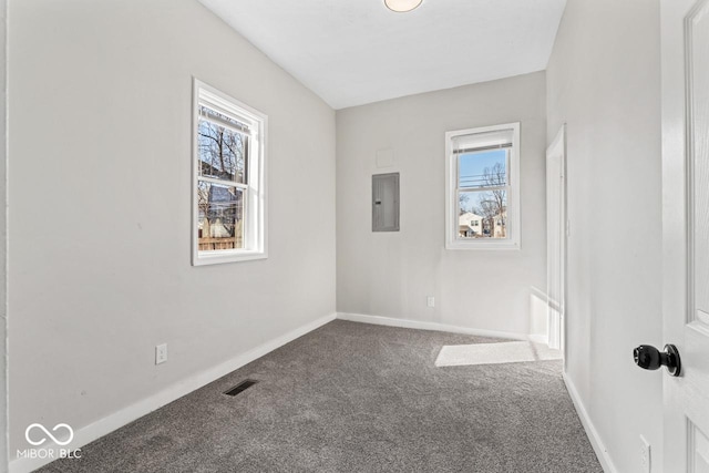 carpeted empty room featuring electric panel, visible vents, and baseboards