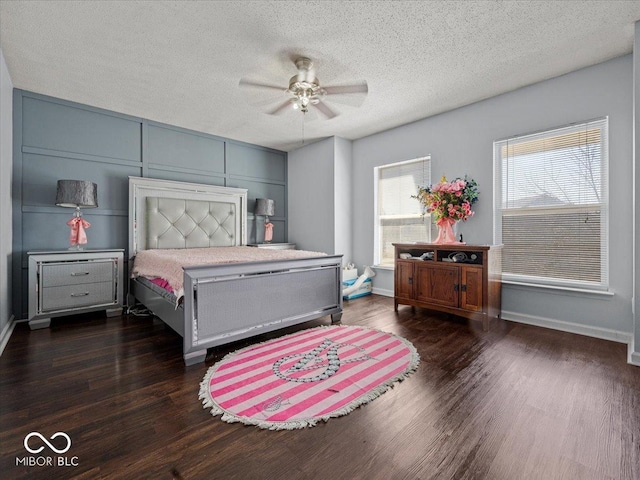 bedroom with dark wood finished floors, baseboards, and a textured ceiling