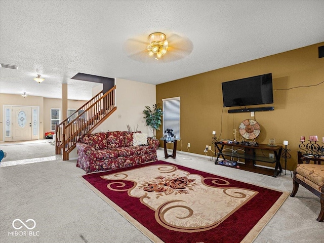 carpeted living area featuring visible vents, a textured ceiling, baseboards, ceiling fan, and stairs