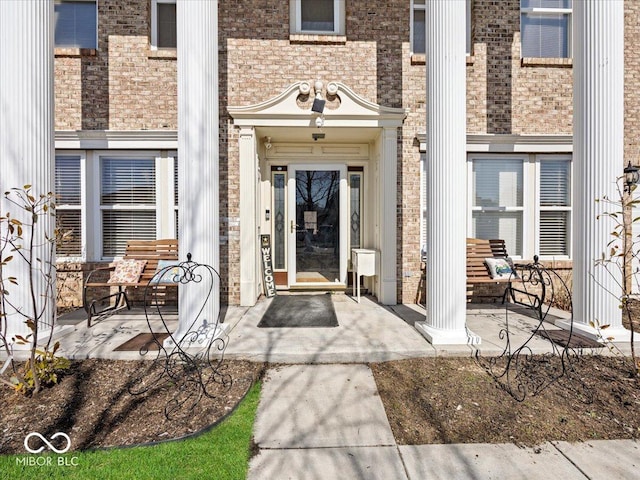 view of exterior entry featuring brick siding and covered porch