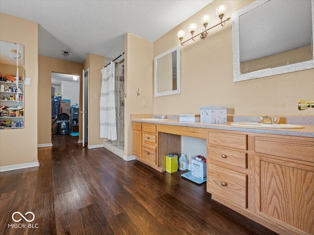 full bath featuring a shower with curtain, a sink, a textured ceiling, wood finished floors, and double vanity