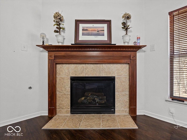 room details with wood finished floors, baseboards, and a tile fireplace