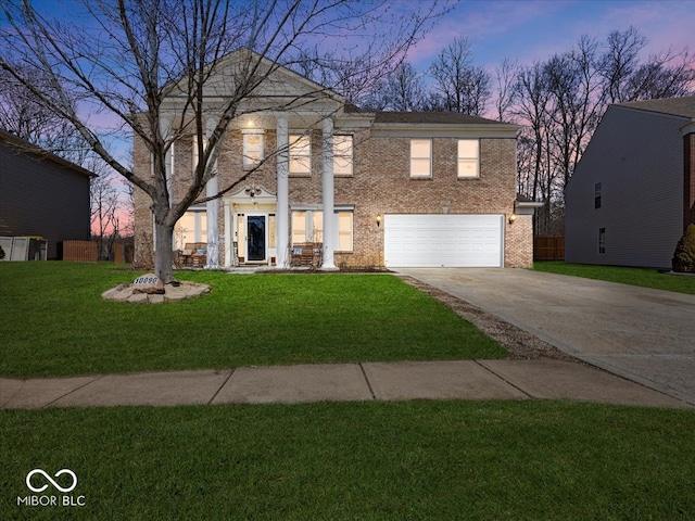 neoclassical / greek revival house with a front lawn, fence, concrete driveway, an attached garage, and brick siding