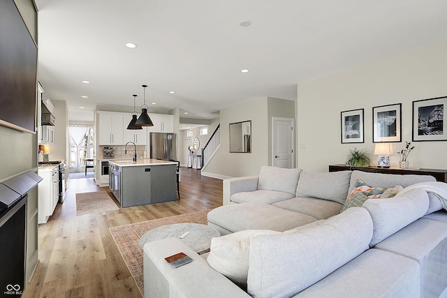 living area with recessed lighting, stairs, and light wood-type flooring