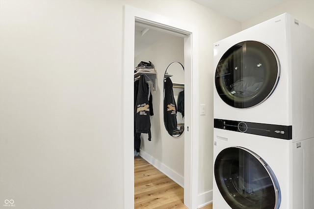 laundry room with baseboards, light wood finished floors, laundry area, and stacked washer / dryer