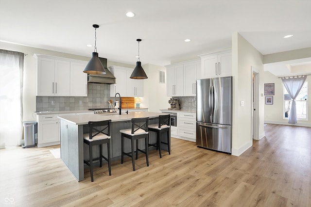 kitchen with stainless steel appliances, a kitchen breakfast bar, light wood-style floors, and light countertops