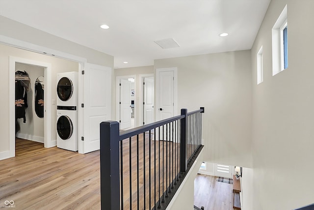 hallway featuring an upstairs landing, stacked washer and clothes dryer, recessed lighting, light wood-style floors, and baseboards