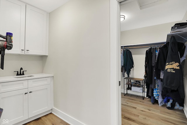 interior space featuring a sink, light wood-type flooring, and baseboards