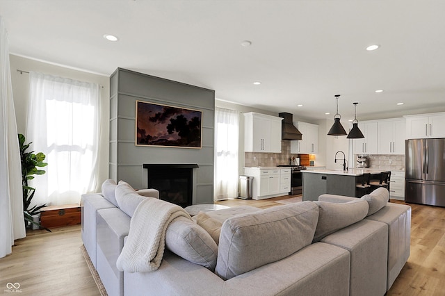 living area featuring a glass covered fireplace, recessed lighting, and light wood-style floors