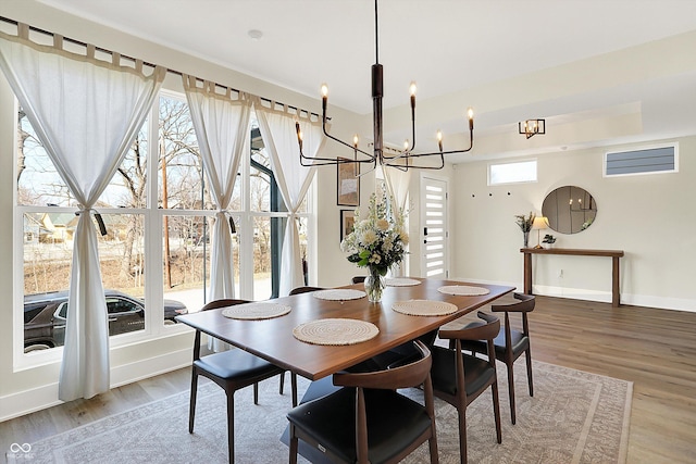 dining space with baseboards, an inviting chandelier, light wood-style flooring, and a healthy amount of sunlight