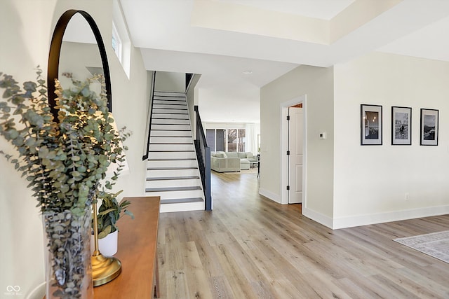 foyer entrance with baseboards, light wood-style floors, and stairs