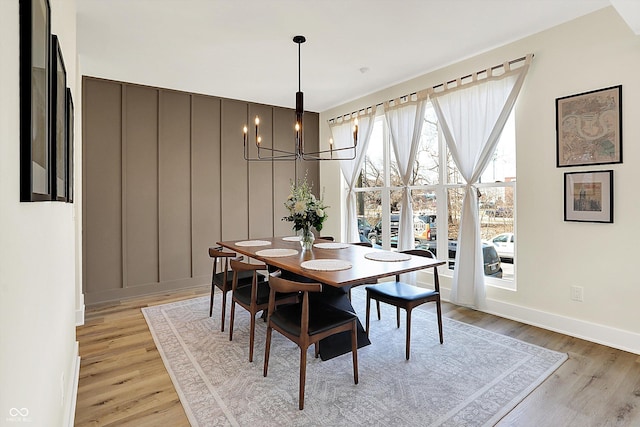 dining area with light wood-style flooring, baseboards, and an inviting chandelier