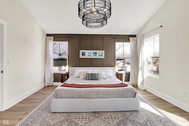 bedroom with vaulted ceiling, baseboards, and wood finished floors