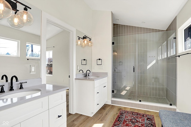 full bath with two vanities, wood finished floors, a stall shower, and a sink