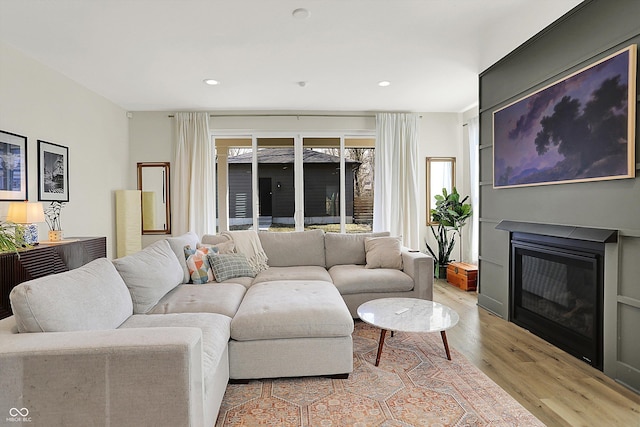 living area with a glass covered fireplace, wood finished floors, and recessed lighting