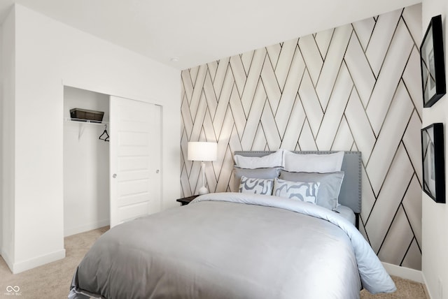 carpeted bedroom featuring a closet, an accent wall, and baseboards