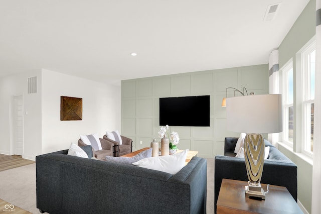 living room with a wealth of natural light, visible vents, and wood finished floors