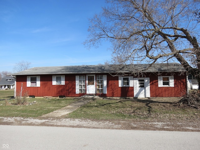 ranch-style home featuring a front lawn and roof with shingles