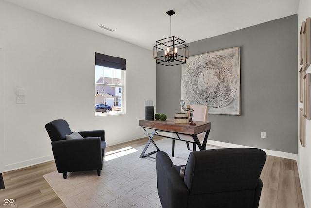 office with a notable chandelier, visible vents, baseboards, and wood finished floors