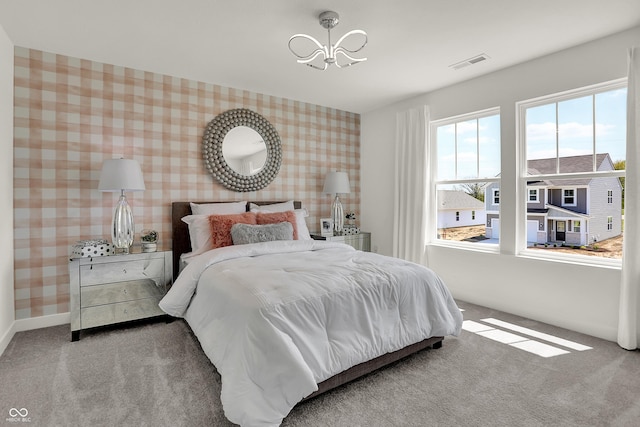 bedroom featuring visible vents, carpet floors, an inviting chandelier, wallpapered walls, and baseboards