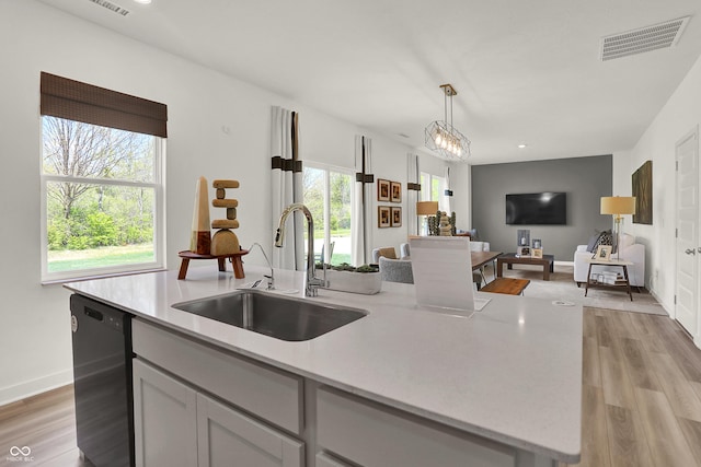 kitchen with visible vents, light wood-style flooring, a sink, dishwasher, and open floor plan