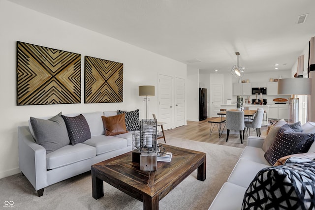 living room with recessed lighting, visible vents, light wood-style flooring, and baseboards