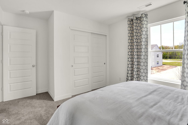 carpeted bedroom featuring visible vents, baseboards, and a closet