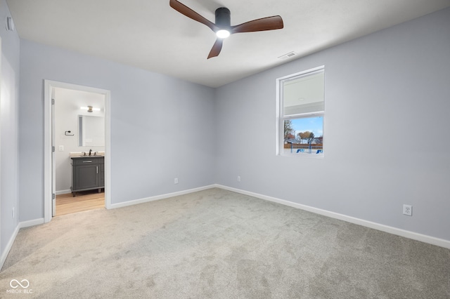 unfurnished bedroom with visible vents, light carpet, a sink, ensuite bath, and baseboards