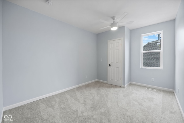 empty room with ceiling fan, visible vents, baseboards, and light carpet