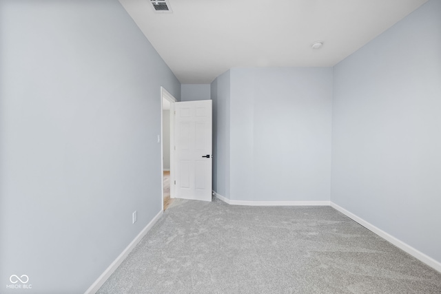 carpeted empty room featuring baseboards and visible vents