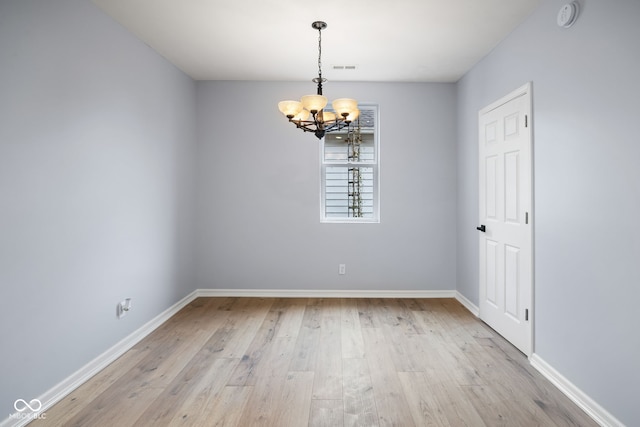 unfurnished room with a notable chandelier, visible vents, light wood-type flooring, and baseboards