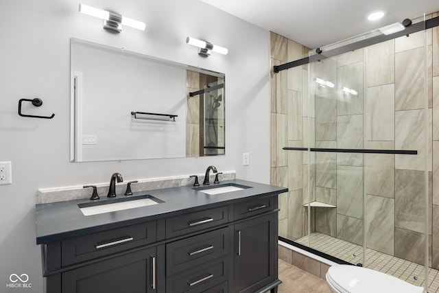 full bath with a sink, toilet, a stall shower, and double vanity