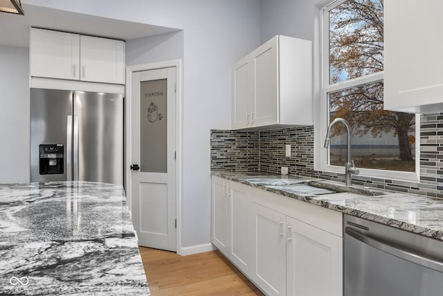 kitchen featuring light wood-type flooring, backsplash, appliances with stainless steel finishes, and white cabinets