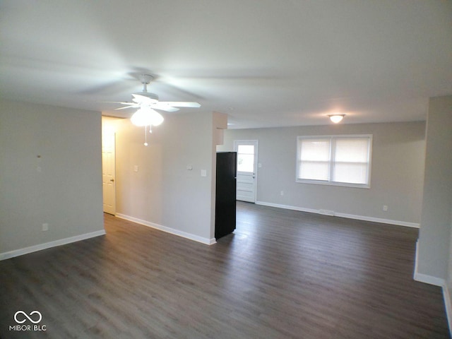 spare room with baseboards, dark wood-style floors, and a ceiling fan